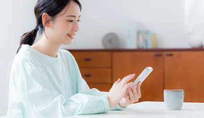 スマートフォンで査定を申し込む女性